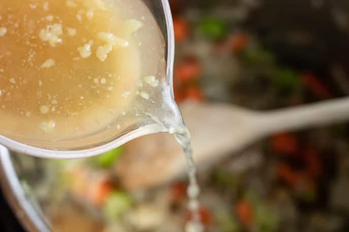 Chicken broth and wine pouring into Instant Pot