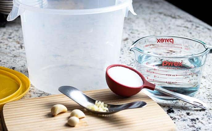 Large container, measuring cup with water, salt, garlic and cutting board from Gourmet Done Skinny