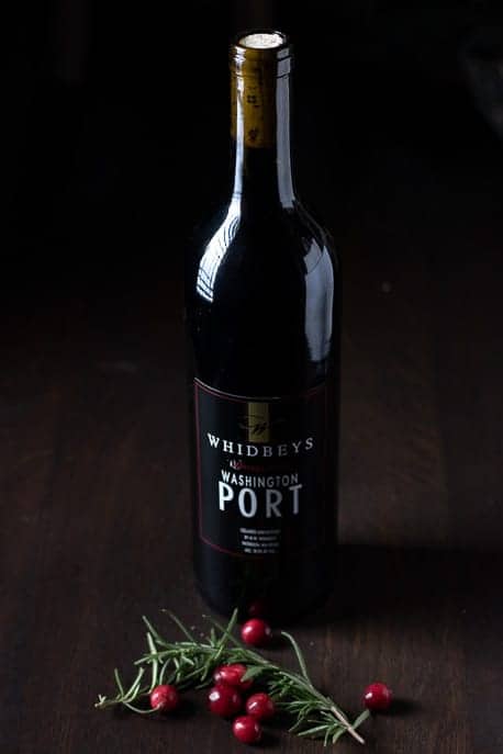 Whidbey Port bottle on a wooden table with fresh rosemary and cranberries