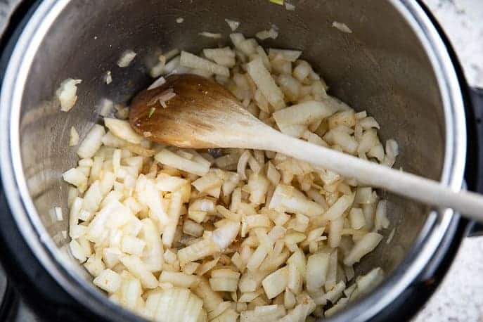 Instant Pot with onions and wooden spoon