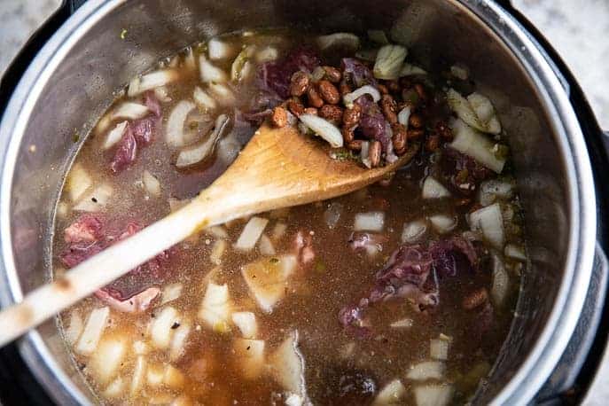 Instant Pot with beans, beef, onions and wooden spoon