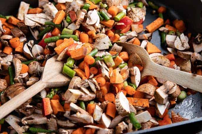 Roasted vegetables in a non stick pan with 2 wooden spoons from Gourmet Done Skinny