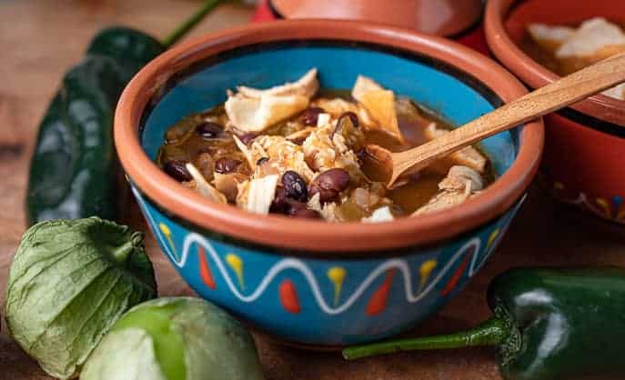 Mexican bowl with Chipotle Chicken Soup, wooden spoon, tomatillos and peppers
