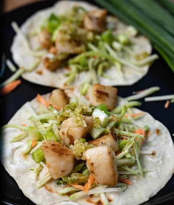 2 Pan Seared Scallop Tacos on a black plate