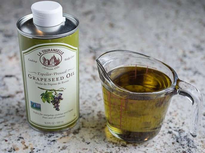 Grapeseed oil and measuring cup with oil on a granite counter top.