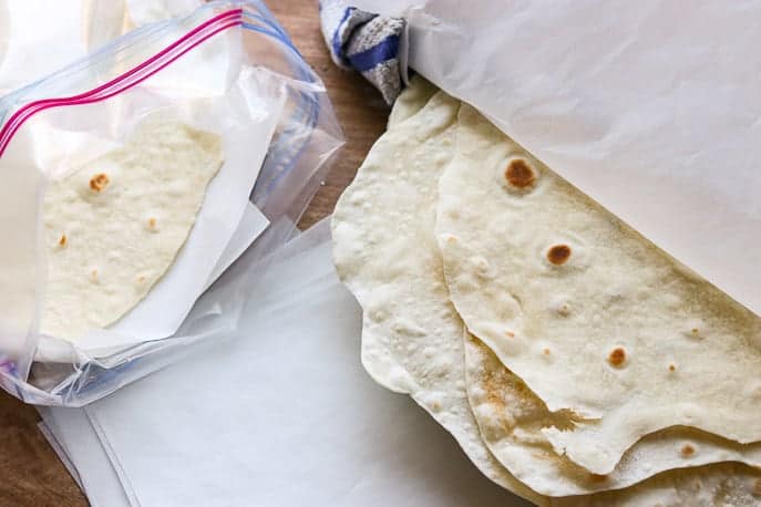 flour tortillas under a towel, in a ziplock bag with parchment paper