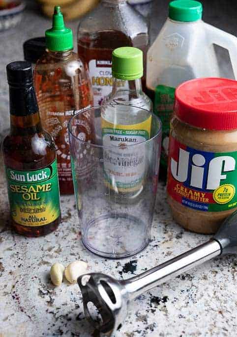 Ingredients for stir fry sauce and immersion blender on a marble counter top