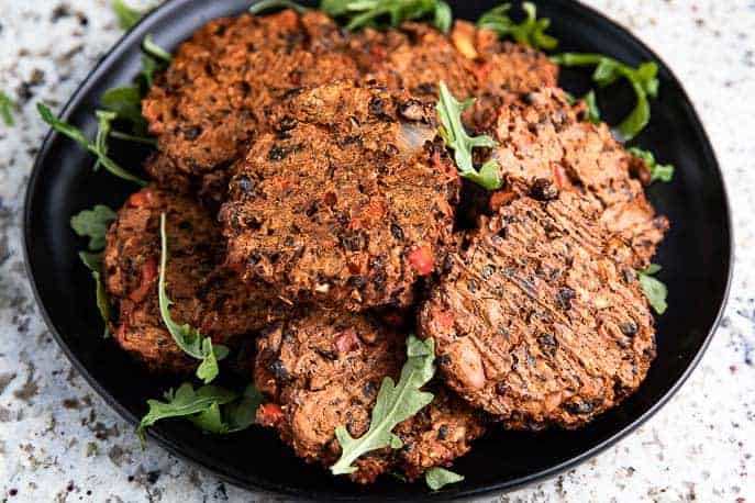 chipotle black bean burgers on a black plate with arugula