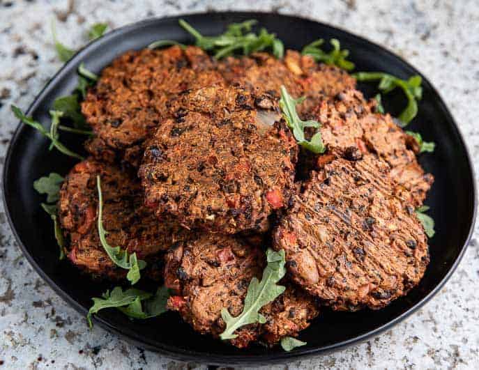 chipotle black bean burgers on a black plate with arugula