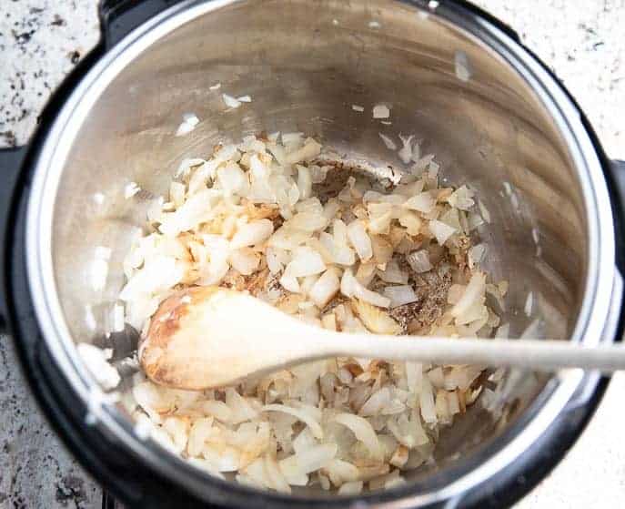 Onions and wooden spoon in an Instant Pot