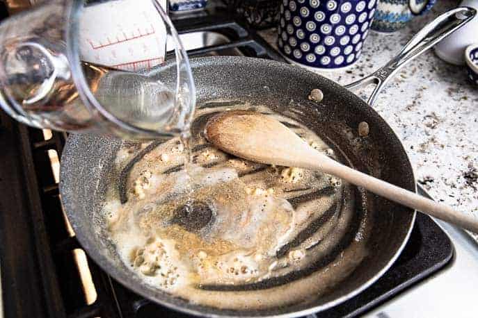 Wine being poured into skillet with melted butter and flour.