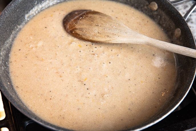 creamy parmesan sauce in a plan with wooden spoon