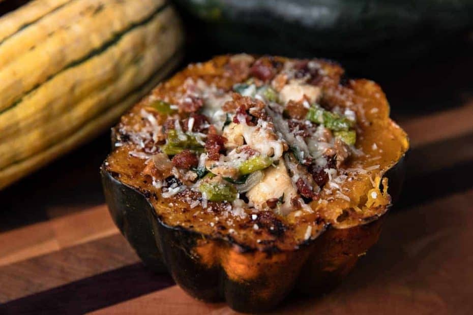 stuffed acorn squash on a wooden board with squash in the background
