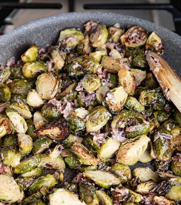 roasted brussels sprouts in a pan with onions and cream sauce