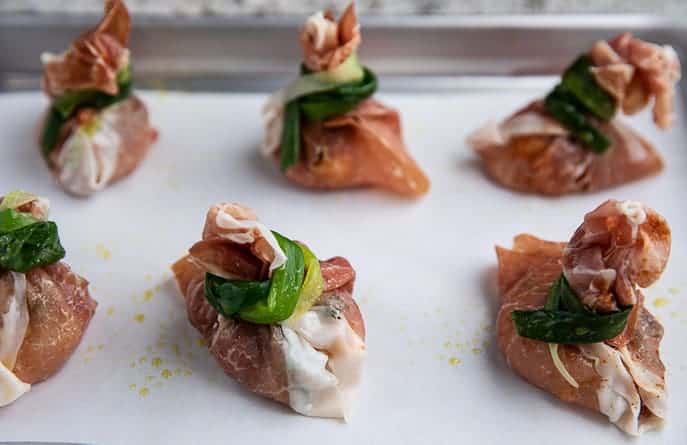 Prosciutto wrapped scallops on a baking sheet with parchment paper