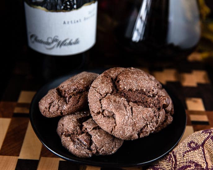 Spicy chocolate snaps on a black plate with wine bottle and glass of wine in the background