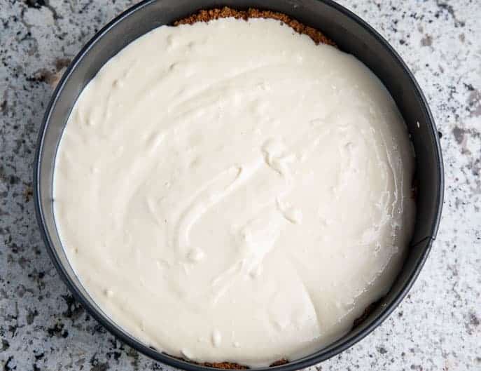 cheesecake mixture in a springform pan on a granite counter top