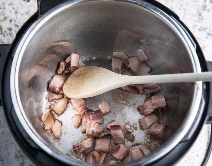 bacon frying with a wooden spoon in the Instant Pot