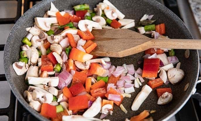 red pepper, onion, mushrooms, asparagus in a skillet with wooden spoon