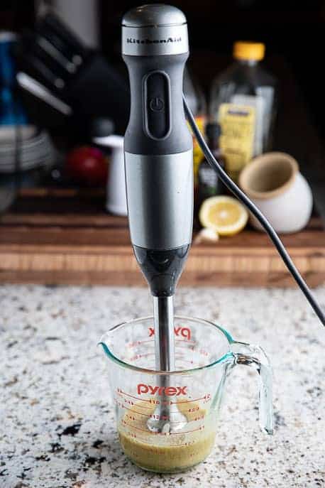 measuring cup with honey mustard dressing and immersion blender on a granite counter