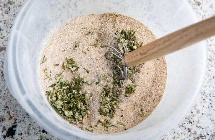 danish whisk in a bucket with flour and herb mixture