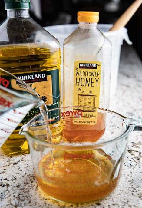 honey, olive oil, measuring cup pouring water into honey and oil mixture