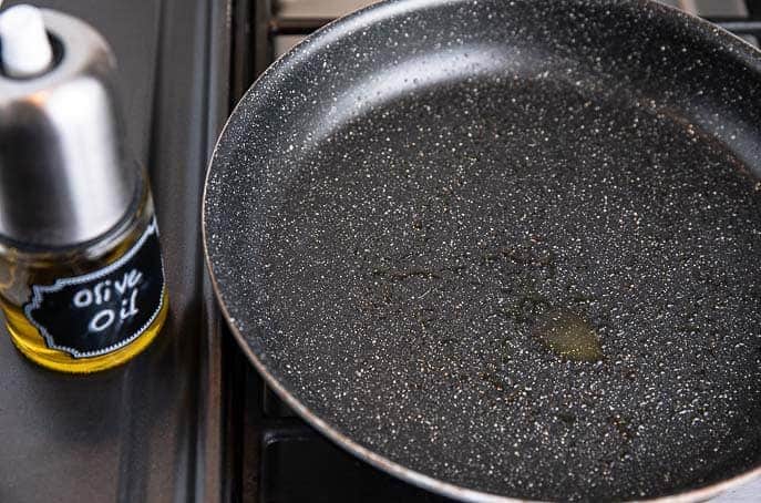 non stick skillet with olive oil spray, olive oil spray next to pan