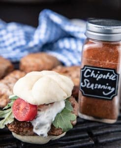 adobo turkey slider with Jalapeno cream on a slider bun with lettuce, sliders in the background, blue napkin, chipotle seasoning