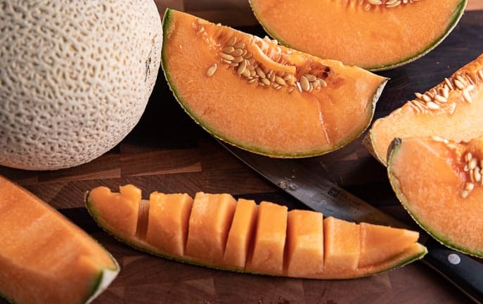 whole melon and cut melon on a wooden board with knife
