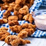air fryer popcorn chicken on a board with sauce