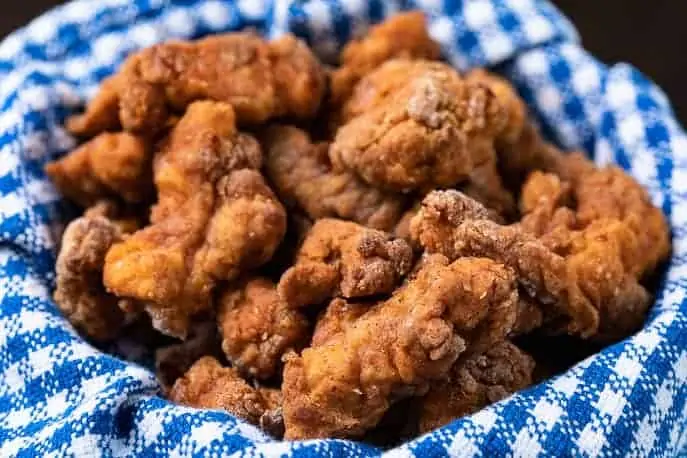air fried popcorn chicken in a basket with blue and white check cloth