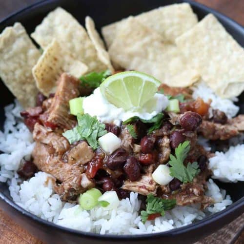 cilantro pork pot in a black bowl with rice and tortilla chips
