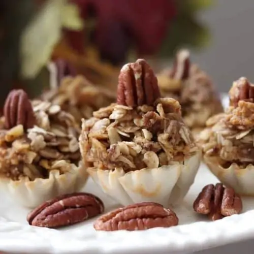 Pumpkin pie tartlets on a cream colored plate with fall leaves in background