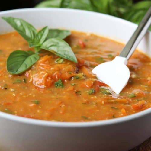 tomato sauce in a white bowl with spatula and basil