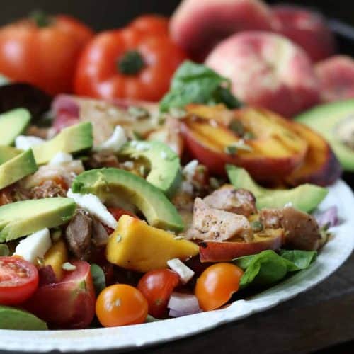 summer chicken tomato salad on a plate with vegetables in background