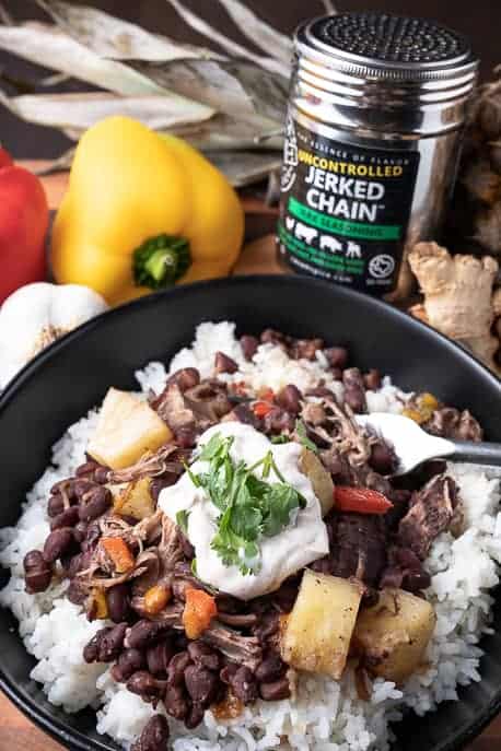 black bowl with Caribbean pork, spice, peppers and pineapple