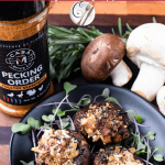 stuffed mushrooms on a black plate with Pecking Order spice and mushrooms