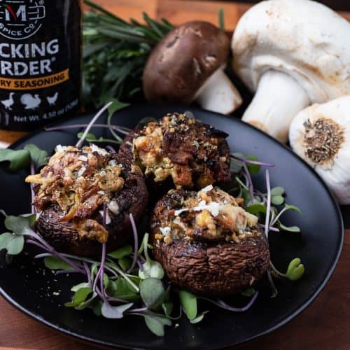 stuffed mushrooms on a black plate with Pecking Order spice and mushrooms