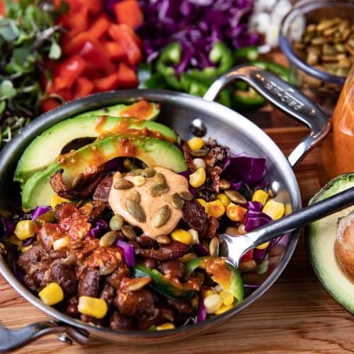 quinoa, pinto bean bowl with vegetables and pepitas on a wooden board