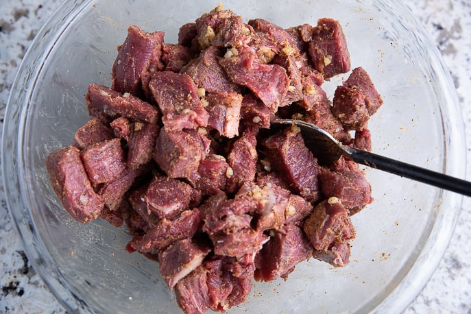 seasoned beef in a glass bowl with spoon