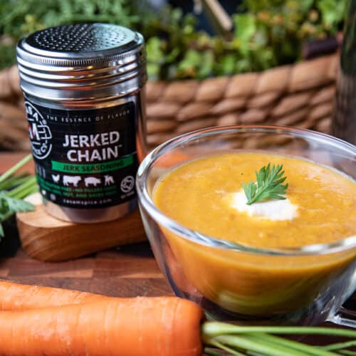 roasted carrot soup in glass cup with spice and carrots on a board