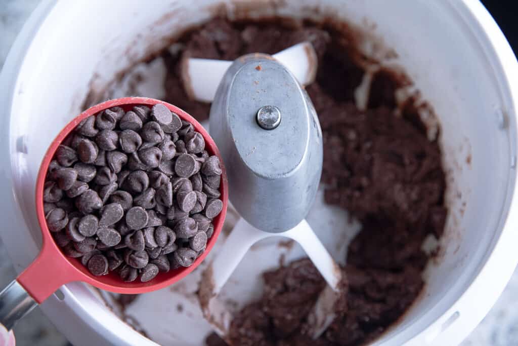 chocolate chips in a measuring cup, mixing bowl with dough