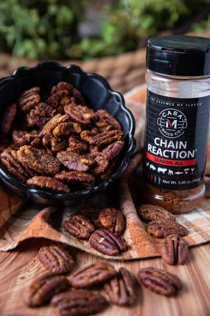 spicy holiday pecans in a black bowl on a cloth with Chain Reaction Spice