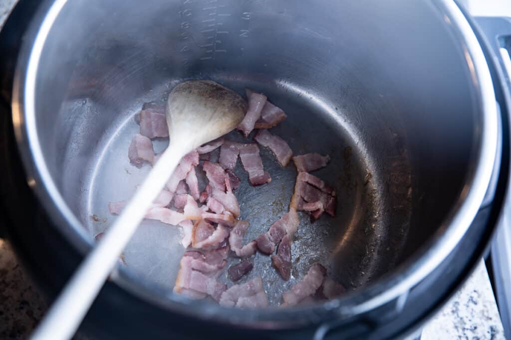 bacon in Instant Pot with wooden spoon