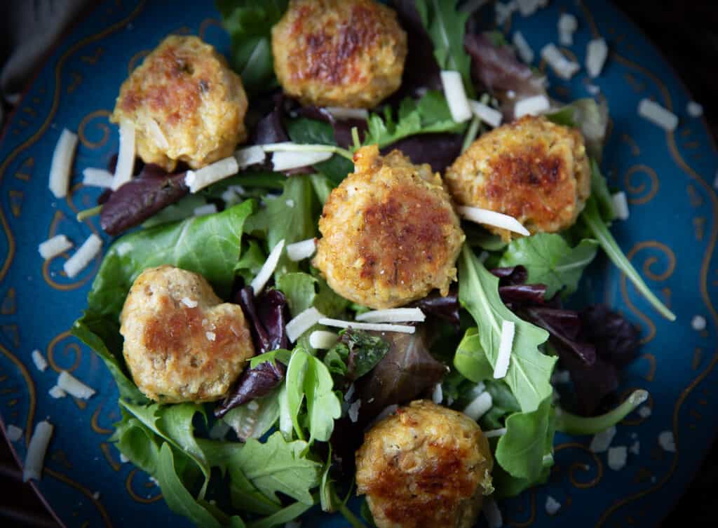 chicken meatballs on a bed of greens with cheese