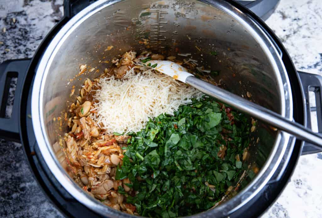 Instant Pot with spinach, parmesan cheese, turkey and spatula
