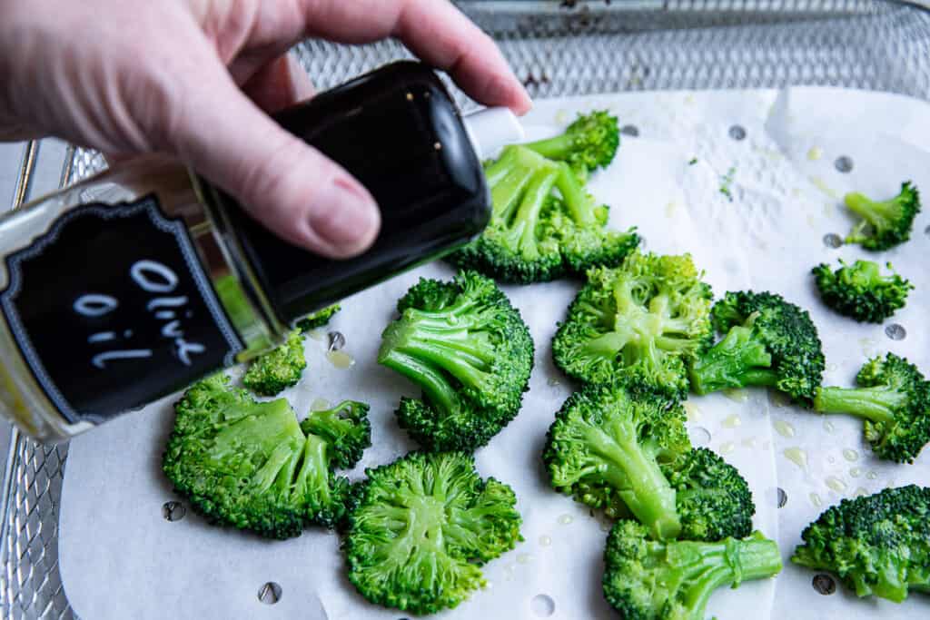olive oil spray over broccoli on a baking sheet