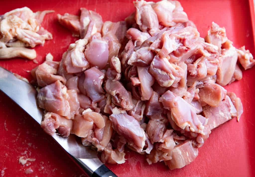 raw chicken on a red cutting board with a knife
