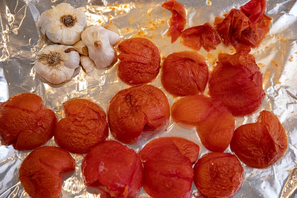 tomatoes and garlic on a baking sheet with foil